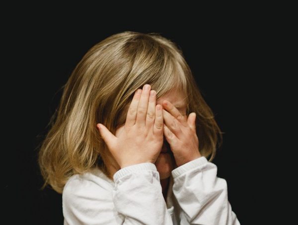 Niña tapándose los ojos.