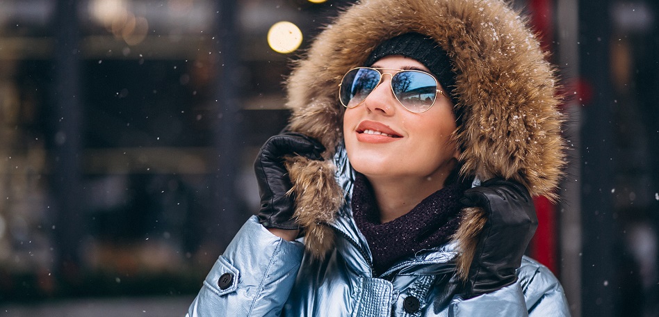 Chica usando gafas de sol para evitar daños en los ojos en el invierno